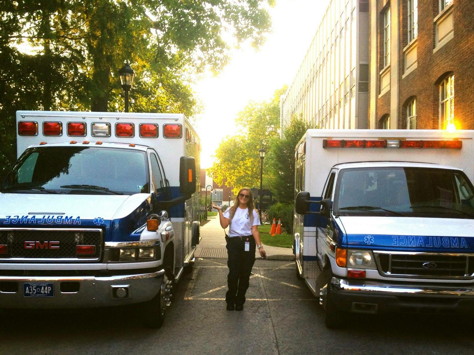Abby Renko, a student EMT, stands between two ambulances on campus. 