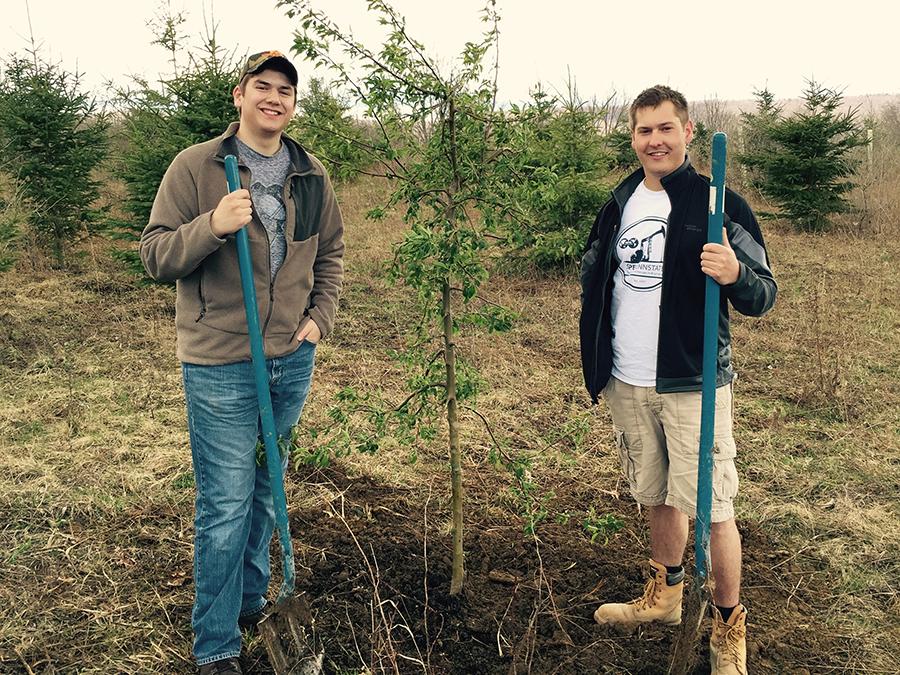 Adam Larson (L) and Tyler Stom (R) stand next to one of the 200 trees planted by Positive Energy, a new student organization created to give back through environmental activities.
