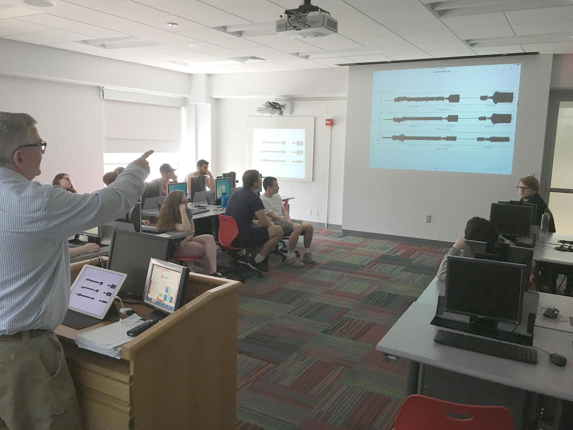 professor points to seismogram on screen in front of class