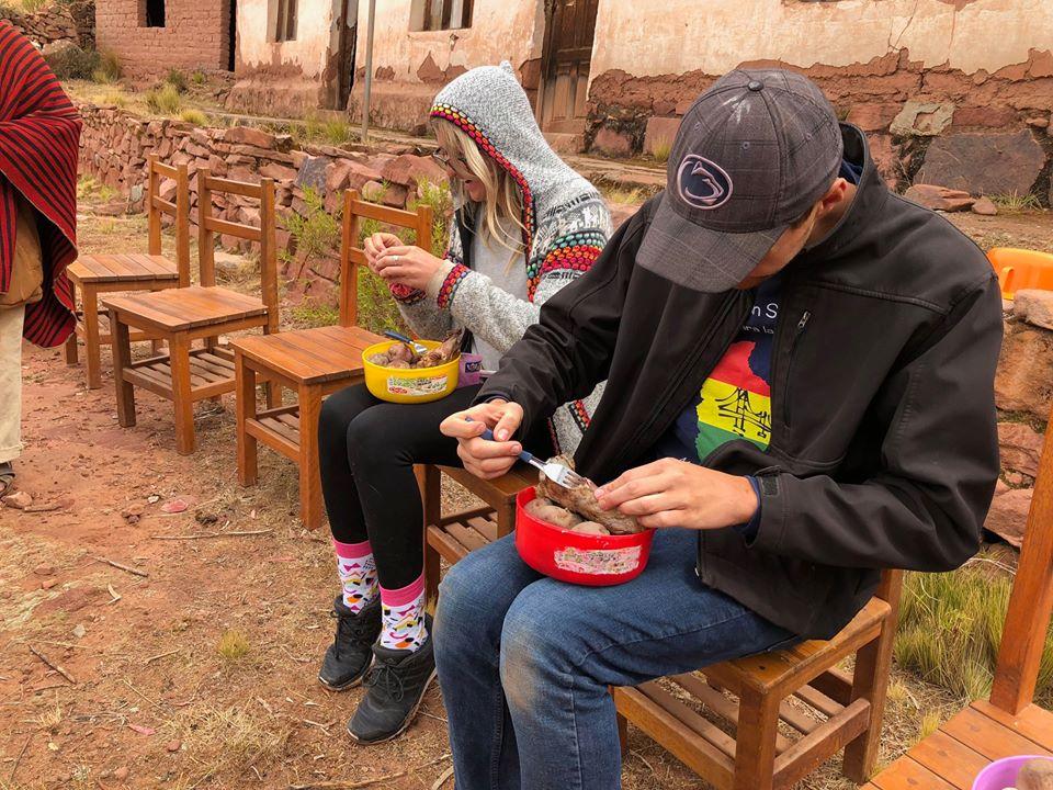 Two students sitting with a bowl of potatoes.