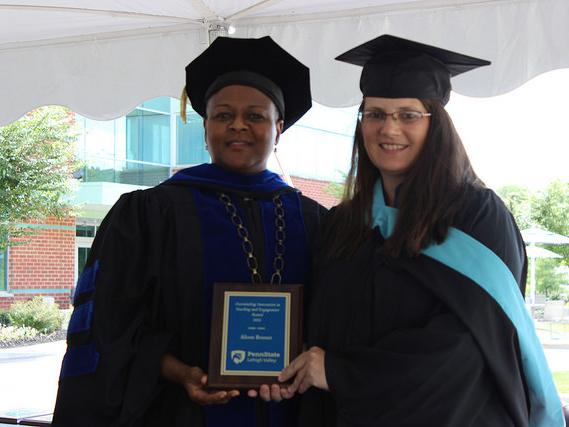 two women pose with a plaque