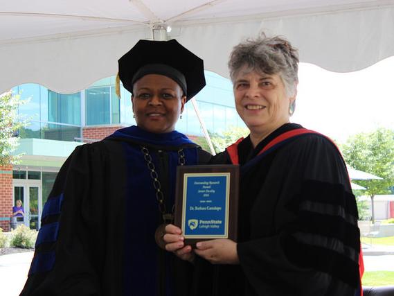 two women pose with a plaque