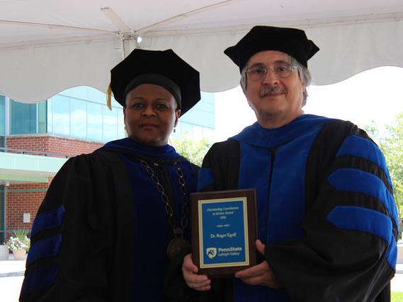 Two people pose with plaque