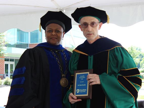 Two people pose with plaque