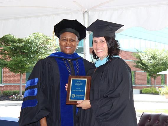 two women pose with a plaque