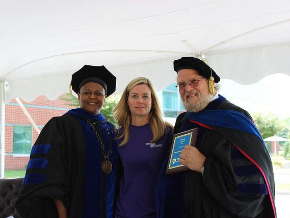 three people pose with plaque