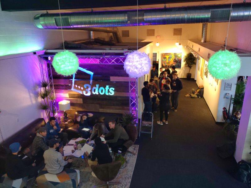 Groups of people are seen from above in a purple-hued event space.
