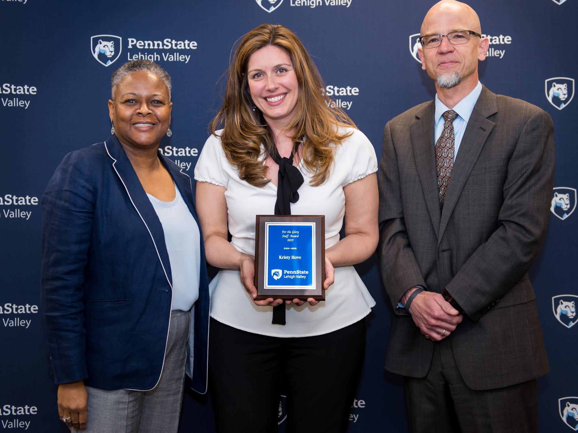 two women and man posing with an award