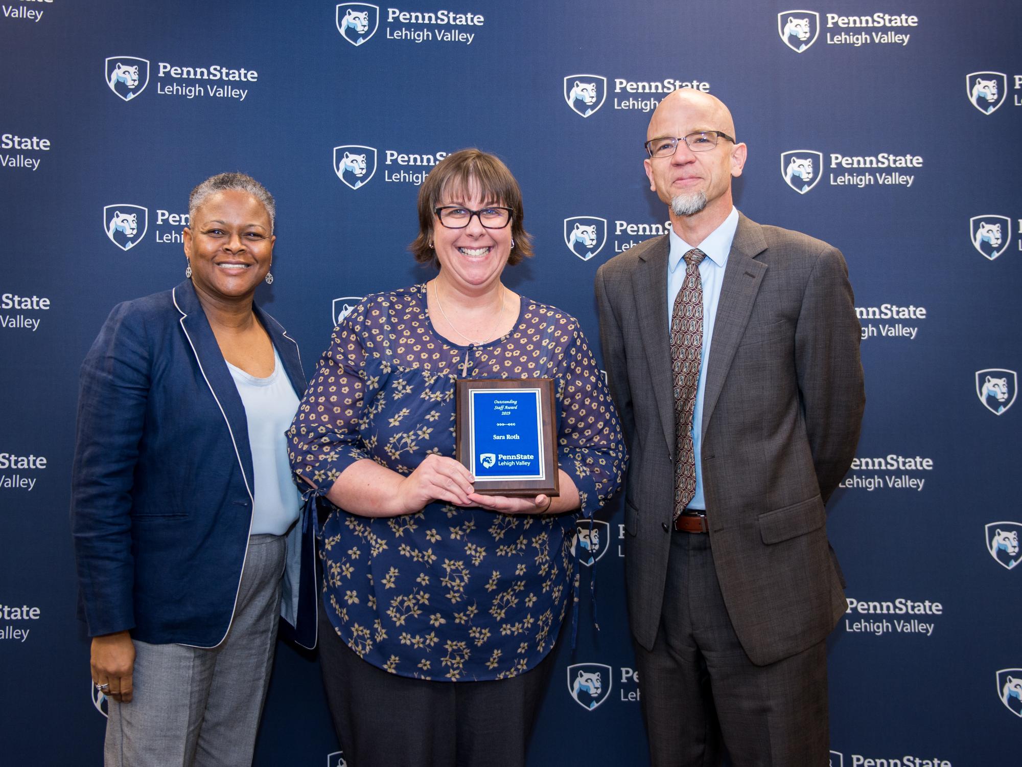 two women and a man posing with an award