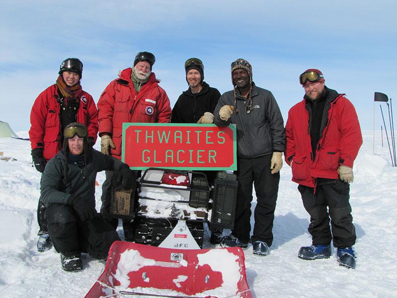The team gathered around a sign on the glacier