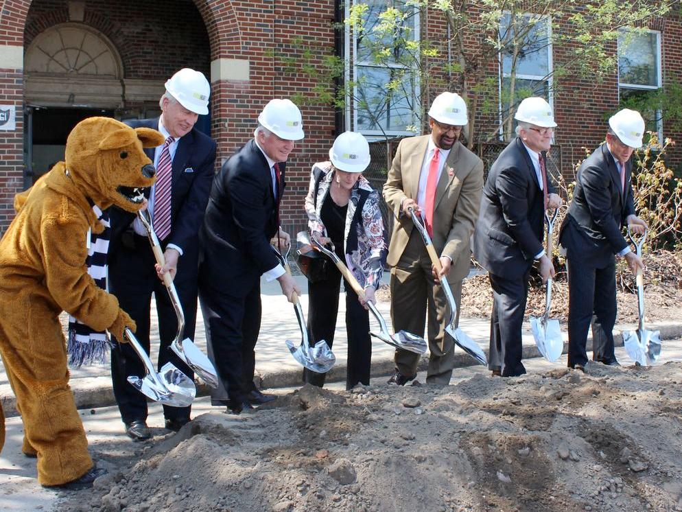 Seven people in a row, including the Nittany Lion mascot, turn dirt with their shovels, breaking ground on the EEB Hub.