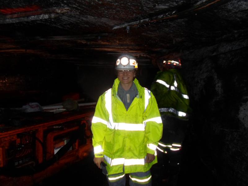 student in dark coal mine wearing reflective jacket
