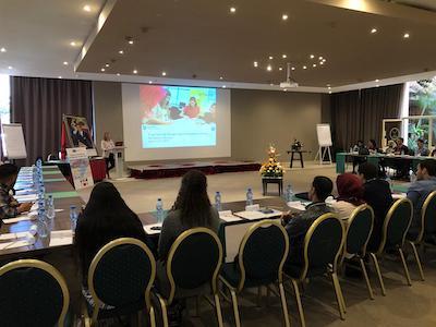 Person stands at a podium and looks out into a room full of people. 