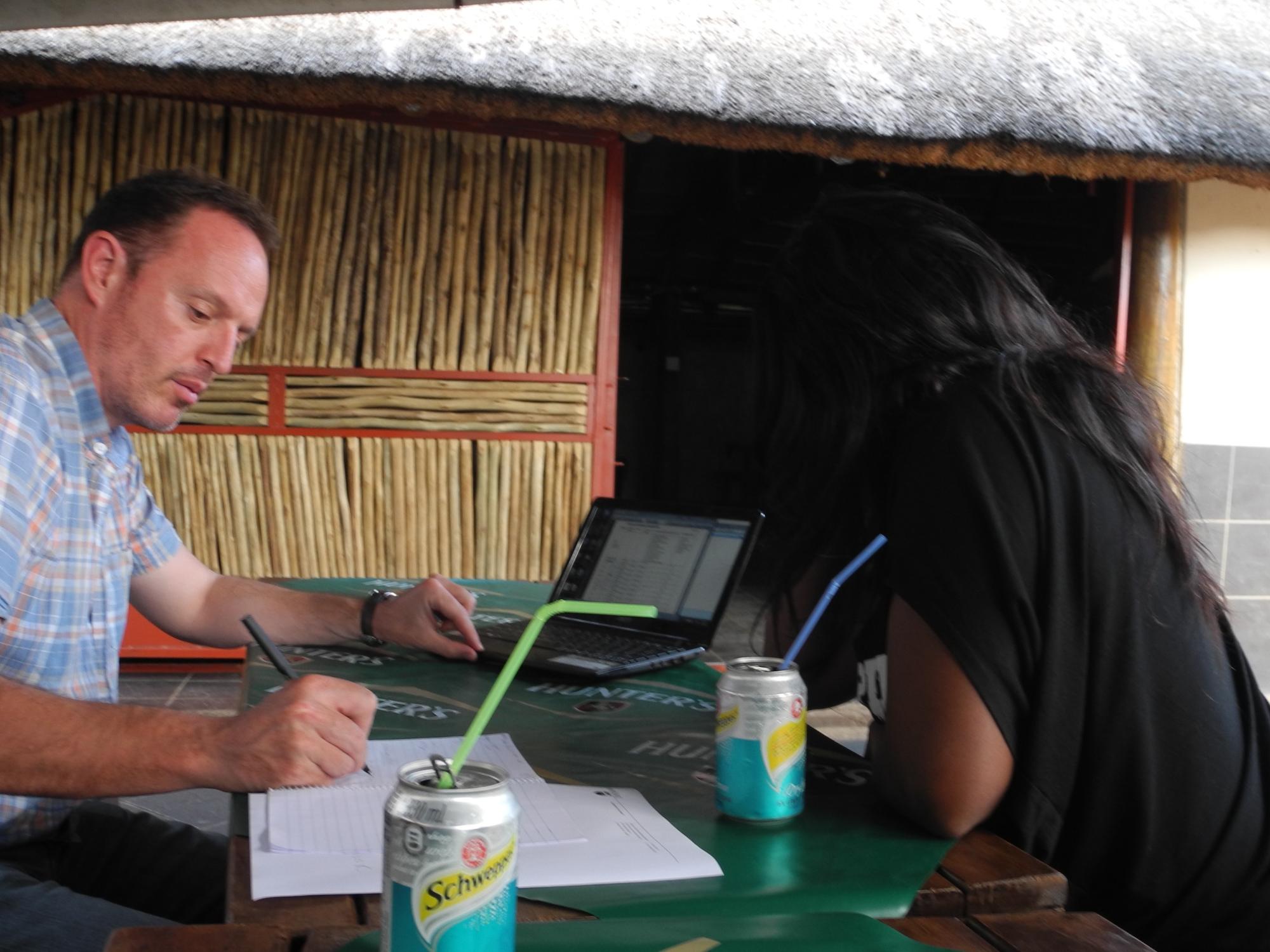researchers writing at a table outside of a hut in South Africa