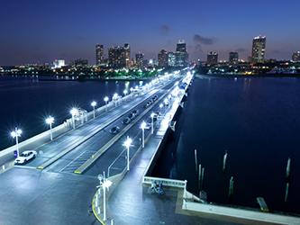 lighted bridge into city against night sky