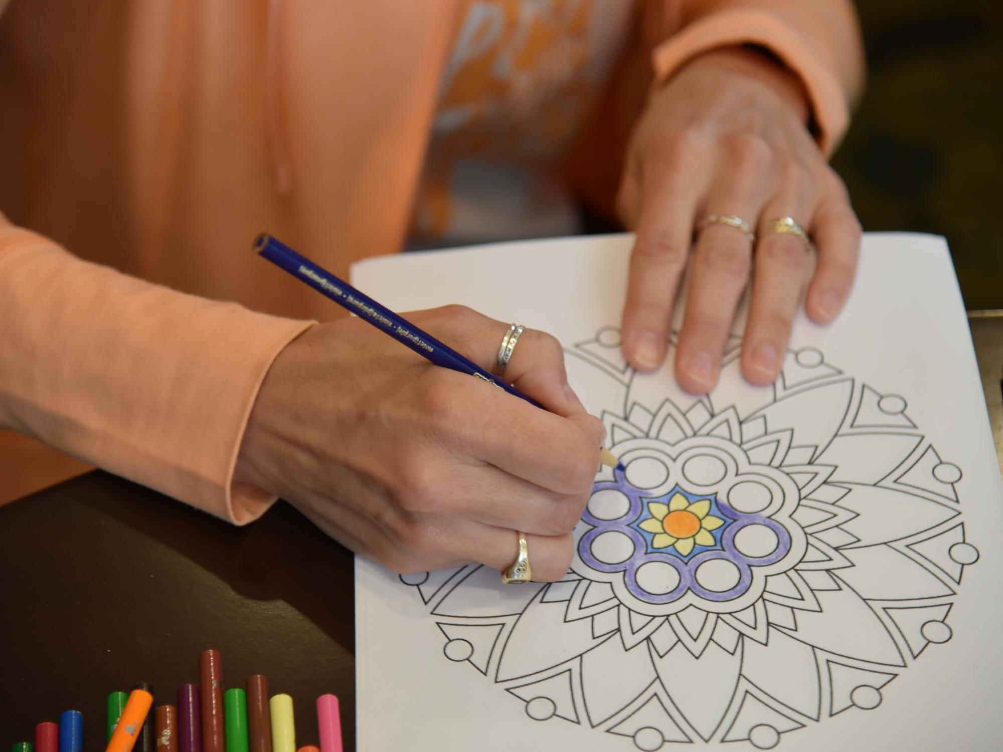 close up of hands, drawing with colored pencil on a geometric pattern