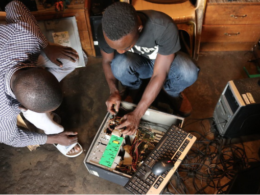 two men fix a discarded computer