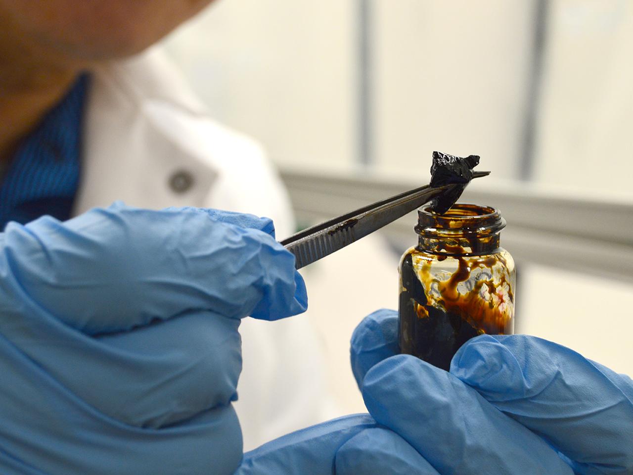 close up shot of hands holding a sample of PetroGel with tweezers