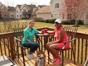 Two women drinking from cups on a deck