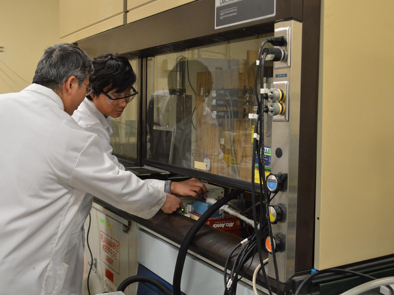 two researchers using a flow reactor system
