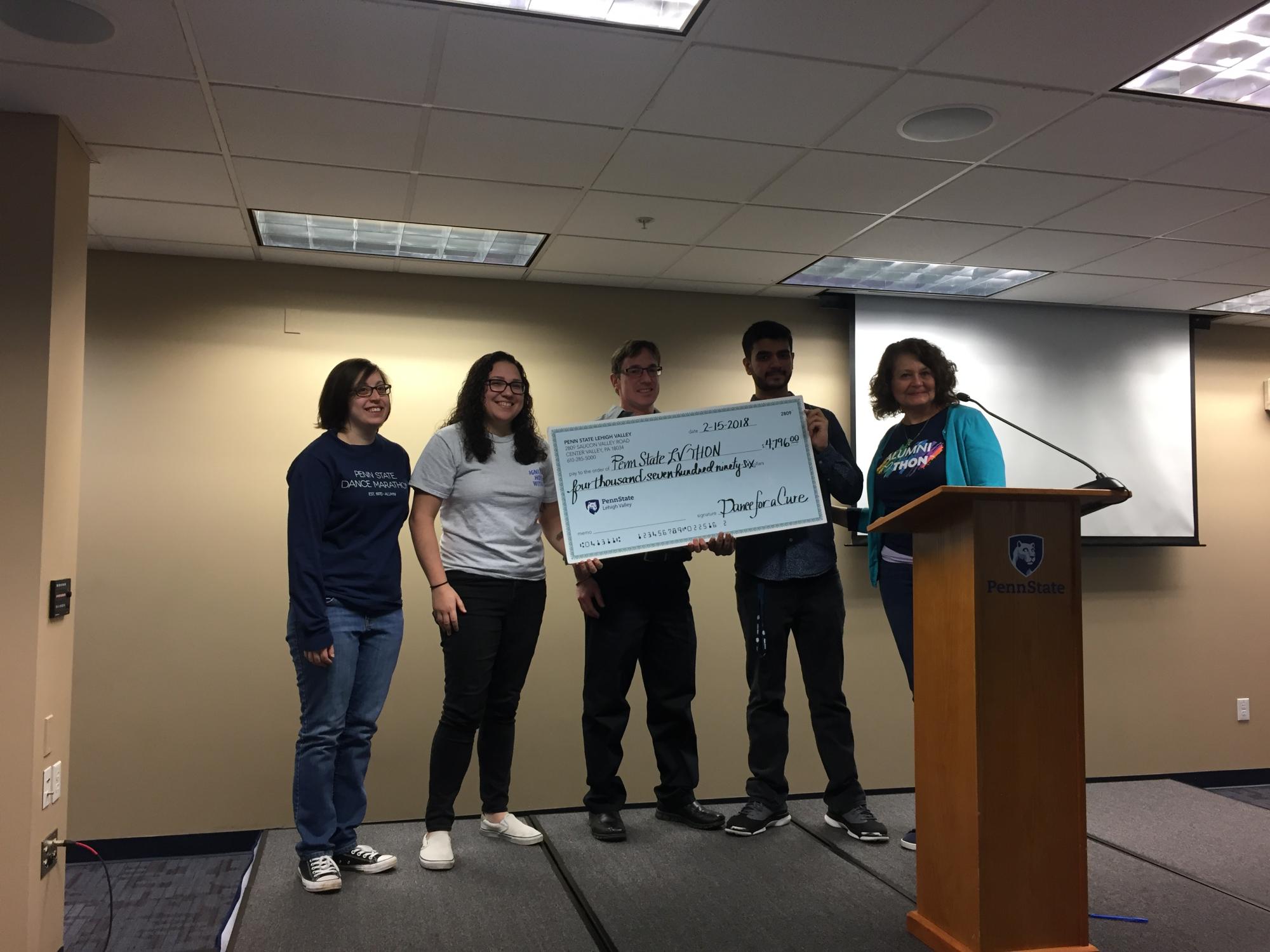 Three people presenting a big check