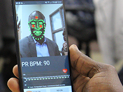 Close up photo of cell phone scanning a man's face to capture pule rate
