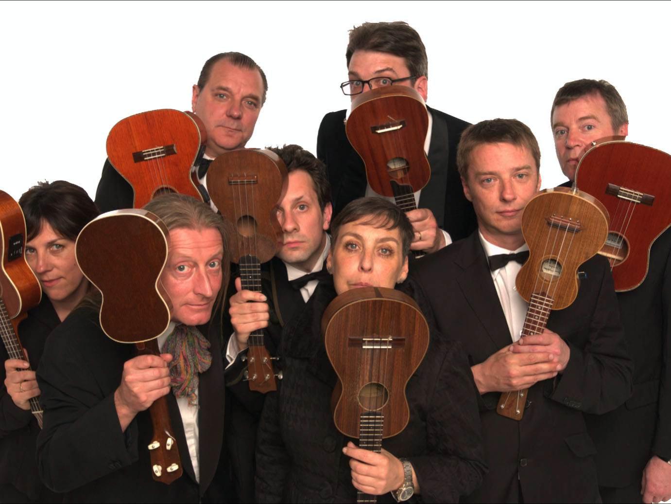 The members of the Ukulele Orchestra of Great Britain hold their instruments in front of their faces.