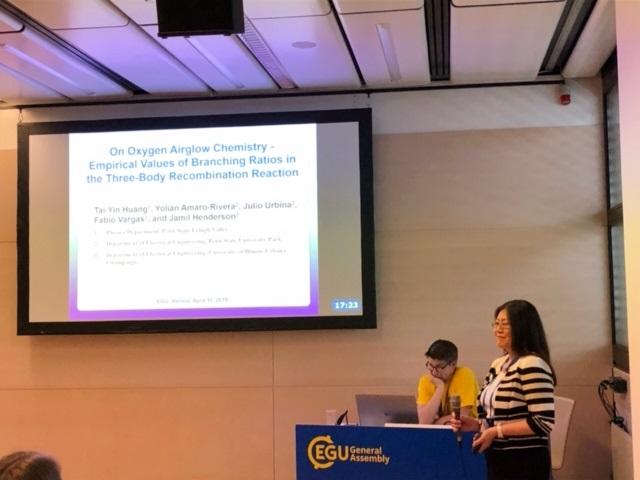 student and professor at podium presenting a slide