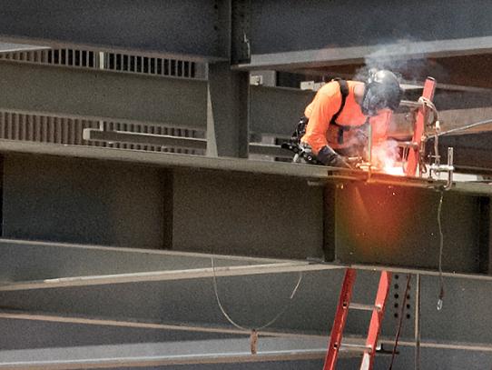 close up shot of construction worker welding steel on the new west campus building