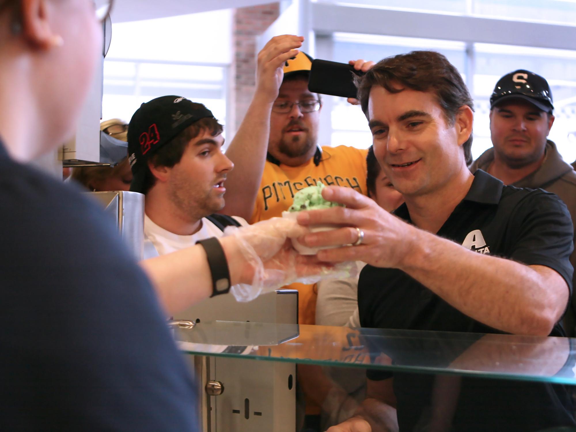 Jeff Gordon reaches over the counter at the Penn State Berkey Creamery for his dish of ice cream.