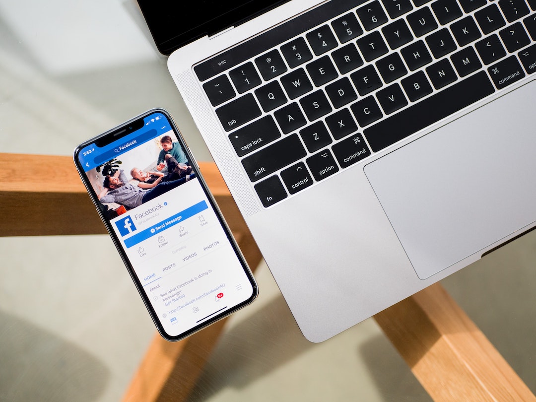 Facebook on a mobile phone alongside a laptop computer