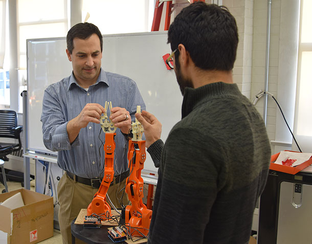 Alan Wagner, assistant professor of aerospace engineering, and graduate student Sagar Lakhmani adjust a pair of Braccio robotic arms on the latest generation of emergency evacuation robots.